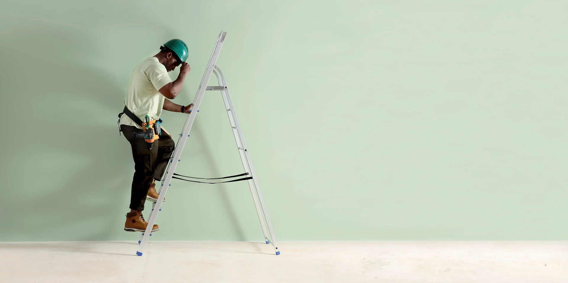 Builder carrying a ladder on a construction site